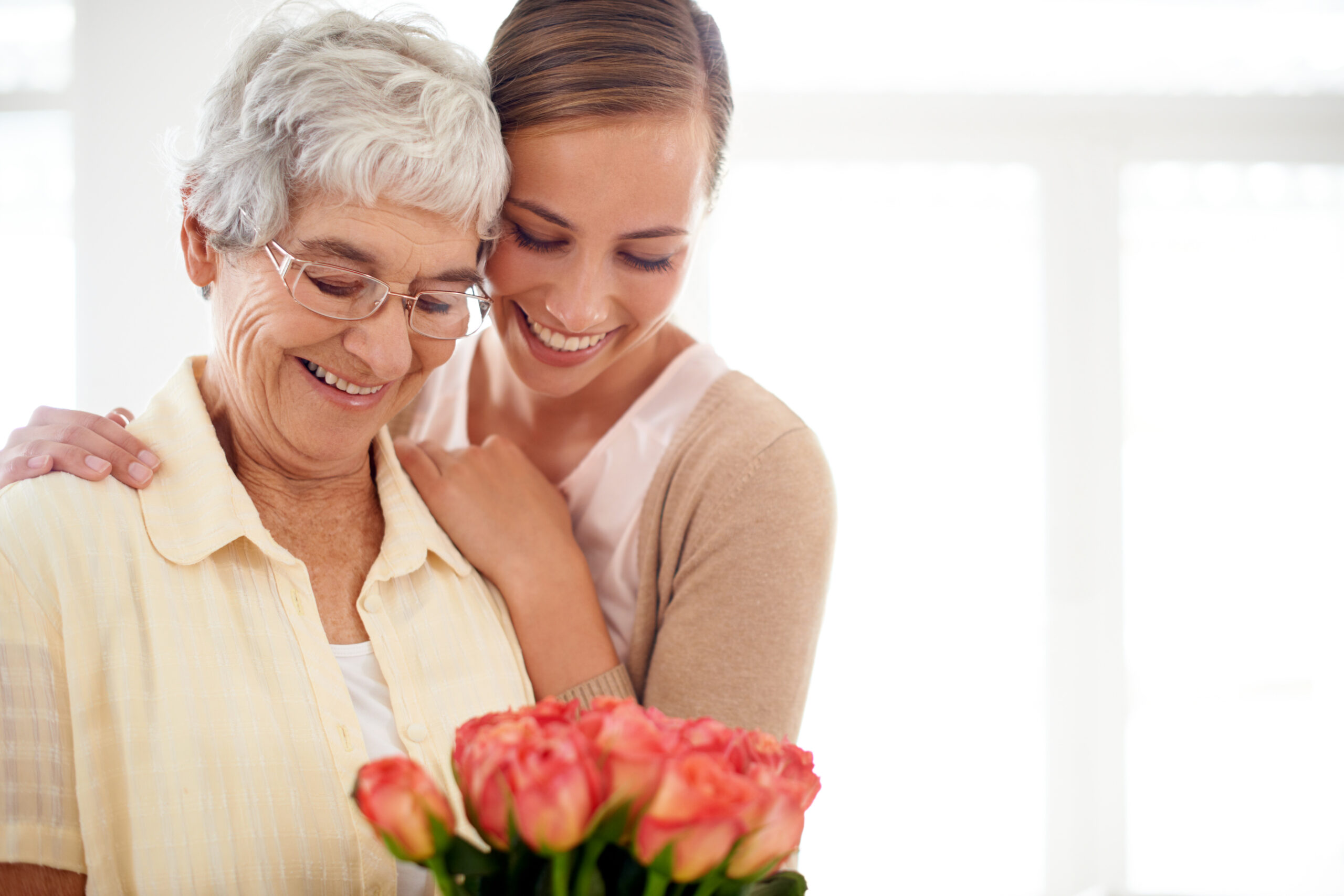 Adult daughter helping her aging mother at home with daily caregiving responsibilities.